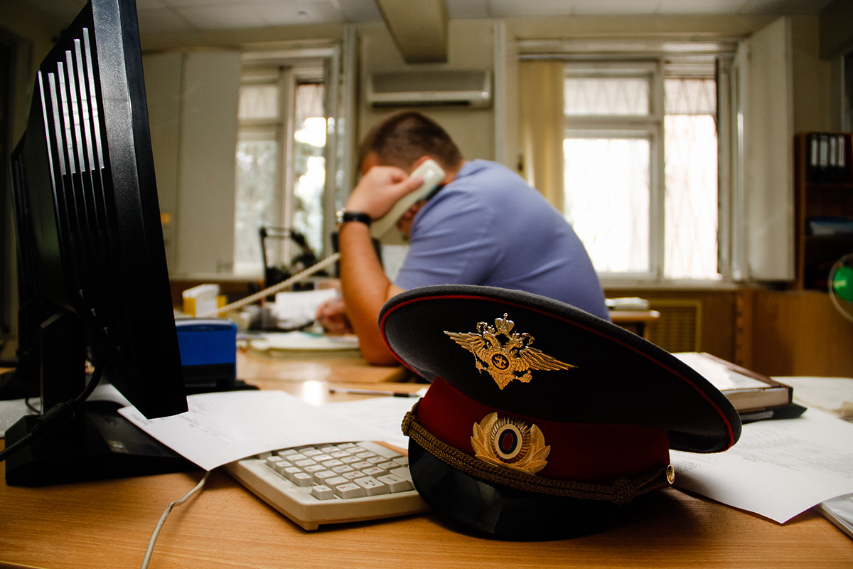 полицейский в кабинете говорит по телефону
