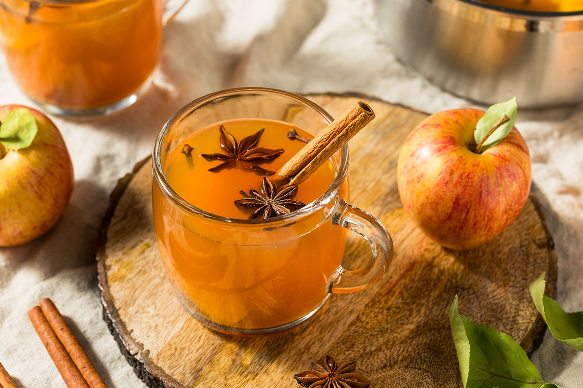стеклянная кружка с яблочным сидром корицей и бадьяном на деревянной доске